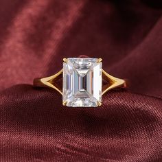 an emerald - cut diamond ring sits on a red cloth