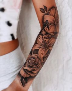 a woman's arm with black and white flowers on the arm, in front of her is a butterfly