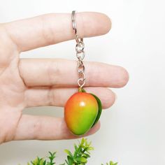 ☼ Mango with leaf from polymer clay.  ☼ One product consists of 1 mango with 1 green leaf.  ☼ 2 variations: red, yellow and green or red and yellow. ☼ Can be used as a keychain, bag charm or necklace . Handmade.  ☼ The height of the product is approximately 8 cm (3 1/4 inches). Total weight 12 gr. ☼ Product will be packed in a little sac, tied with hook. ☼ Orders are shipped as registered mail with tracking number. ☼ More keychains here https://www.etsy.com/shop/MarGoGiftsStudio?ref=l2-shopheader-name§ion_id=23448322 Polymer Clay Fruit, Fruit Keychain, Mango Bag, Clay Fruit, Mango Bags, Clay Keychain, Food Jewelry, Keychain Bag, Metal Keychain