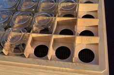 a wooden box filled with lots of clear plastic cups on top of a countertop