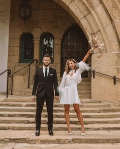 a man and woman are standing on some steps holding their hands up in the air