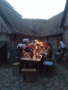 a group of people sitting around a table with candles in front of them on the ground