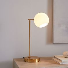 a table with a lamp on it next to some books and a painting in the background