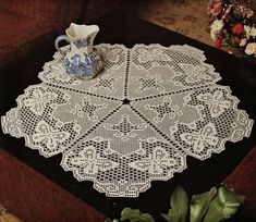 a white doily sitting on top of a table next to a potted plant