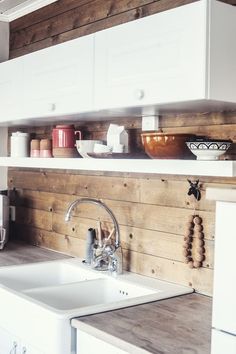 a kitchen with wooden walls and white cabinets