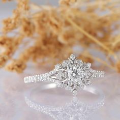 a white gold engagement ring with diamonds on the side and flowers in the back ground