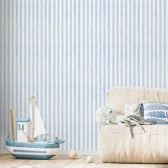 a living room with blue striped wallpaper and a white couch in front of it