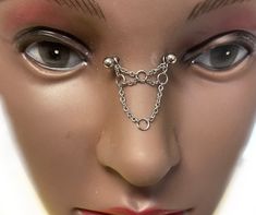 a mannequin's face with chains attached to the nose and eye ring