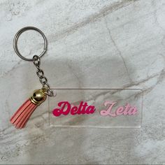 a plastic keychain with a tassel on it that says delta zeia