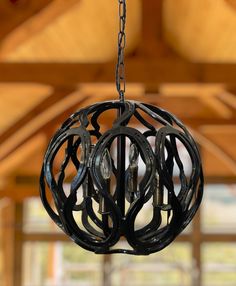 a black chandelier hanging from a ceiling in a room with wooden beams and windows