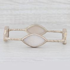 This lovely new bracelet is an authentic Nina Nguyen piece. This bracelet has a retail price of $495. Gem: Natural White Quartz Metal: Sterling Silver Weight: 22.6 Grams  Stamps: 925 nn Style: Bangle Bracelet Closure: Pull Over Inner Circumference: 8 1/4" Width: 15.7 mm - 2.5 mm Each piece is thoroughly examined and refinished as needed by our professional jewelers, graded by our in-house GIA (Gemological Institute of America) Graduate Gemologist, and inspected for quality before being carefully packaged and promptly shipped. [SKU: A3206] White Stackable Metal Jewelry, Elegant Natural Stones Cuff Bracelet, Elegant Natural Stone Cuff Bangle, Elegant Natural Stones Cuff Bangle Bracelet, White Metal Stackable Jewelry, Luxury Natural Stones Bracelets, Elegant Cuff Bracelet With Natural Stones, Elegant Metal Cuff Bracelet With Gemstone, Elegant Metal Bracelets With Natural Stones