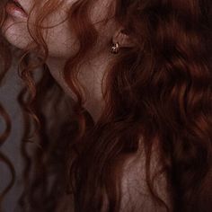 a woman with long red hair is staring into the distance