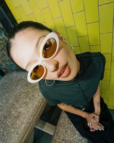 a woman with sunglasses on her head is standing in front of a yellow tiled wall