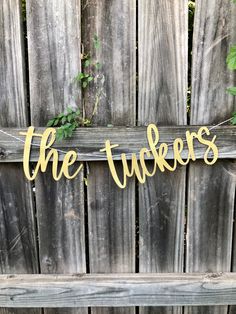 a wooden fence with the word the tuckers hanging from it's side, in gold foil