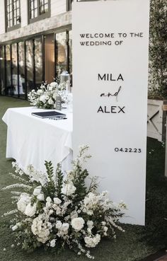 a table with white flowers on it and a sign that says welcome to the wedding of mia and alex