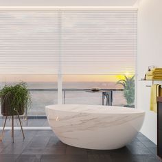 a bath tub sitting next to a window with blinds on the windowsill and a potted plant in front of it