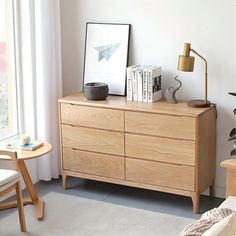 a living room with a dresser, chair and pictures on the wall next to it