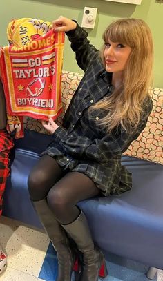 a woman sitting on a blue bench holding up a bag with the name taylor's boyfren