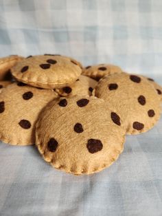 four cookies with chocolate dots are on a blue and white checkered cloth