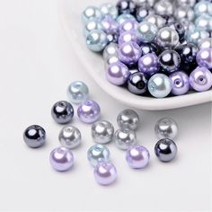 a white bowl filled with lots of purple and silver pearls