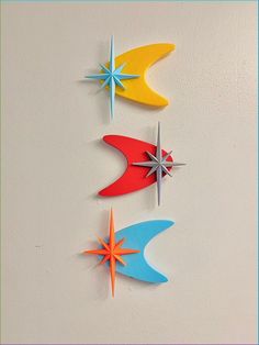 three colorful paper stars are hanging on the wall