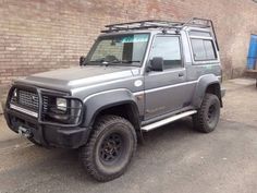 an suv parked in front of a brick wall