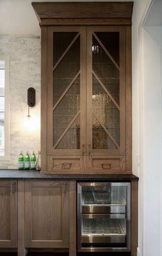 a large wooden cabinet with glass doors in a kitchen next to a sink and stove