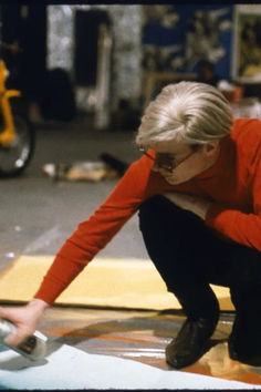 an older woman is painting on the floor