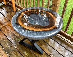 an outdoor table on a deck with water coming out of the top and wood in the bottom