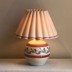 a lamp that is sitting on top of a table next to a white cloth covered wall