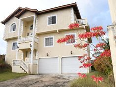 a two story house with red flowers in the front yard