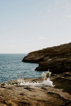 an outdoor wedding setup on the rocks by the ocean