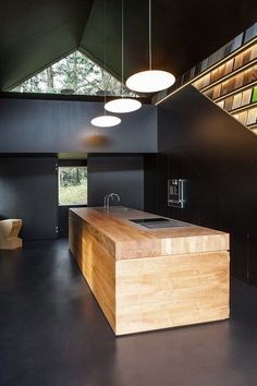 an open kitchen with black walls and wooden counter tops, along with modern lighting fixtures