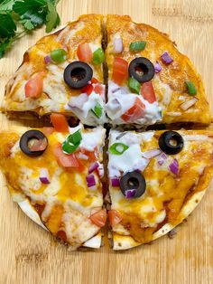 a pizza with several toppings cut into four pieces on a cutting board next to some parsley