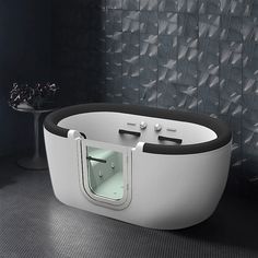 a white bath tub sitting on top of a floor next to a black and white wall