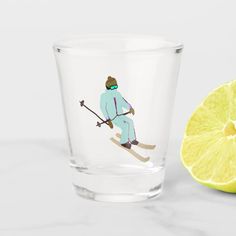 a glass with a skier on it next to a slice of lime and a lemon