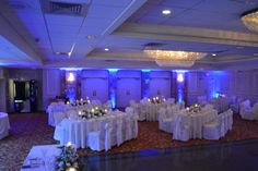 the banquet room is decorated with white linens and blue lighting