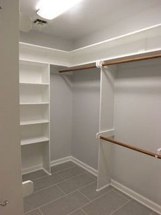 an empty walk in closet with white walls and shelving unit on the far wall