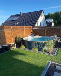 an outdoor hot tub in the middle of a yard with grass and plants around it