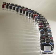 a row of different colored nail polish bottles lined up on a white surface with one bottle in the middle