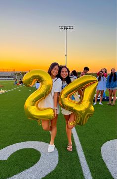 two girls are standing on the field with balloons in the shape of numbers that spell out the number twenty