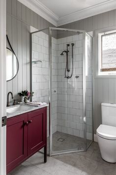 a white toilet sitting next to a walk in shower under a bathroom mirror and sink