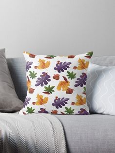 a couch with some pillows on it and one pillow has an orange, purple, yellow and green leaf pattern