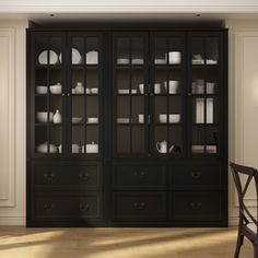 a black china cabinet with glass doors in a dining room area, next to a chair and table