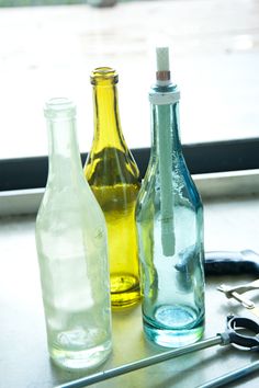 three different colored bottles sitting on top of a table next to scissors and pliers