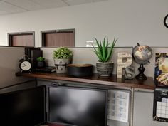 an office cubicle with desk, computer monitor and clock