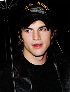 a young man wearing a us army hat and holding an umbrella in front of him