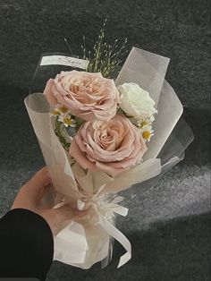 a hand holding a bouquet of flowers on top of a gray carpeted flooring