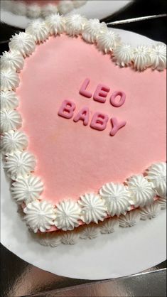 a heart shaped cake with the words leo baby written in frosting on it's side