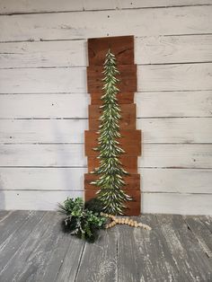 a small christmas tree sitting on top of a wooden table next to a potted plant